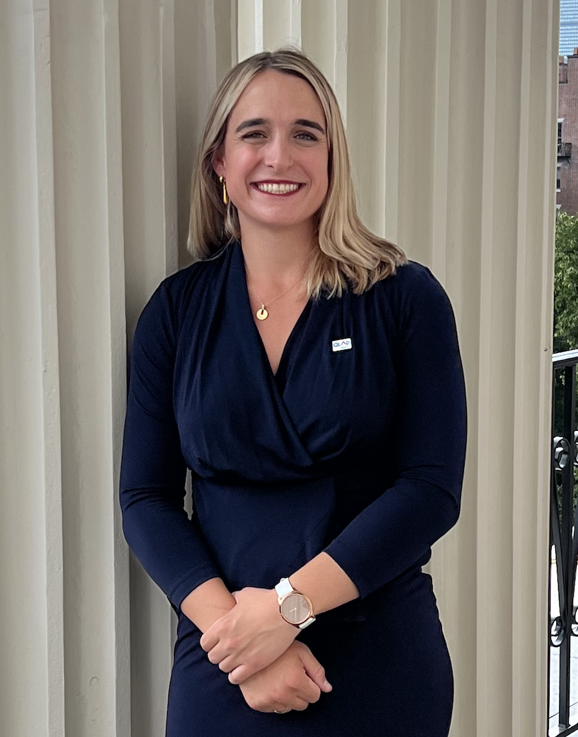 blonde white woman wearing a dark blue dress and smiling